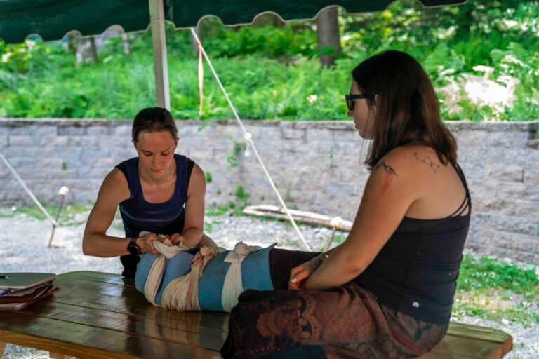 Woman bandaging another woman's leg, representing skin treatment care