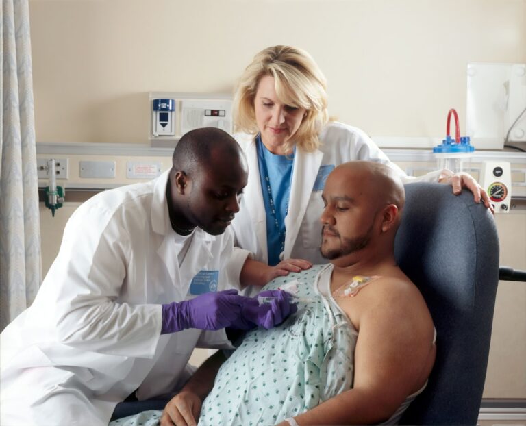 Patient receiving chemotherapy treatment with a nurse assisting