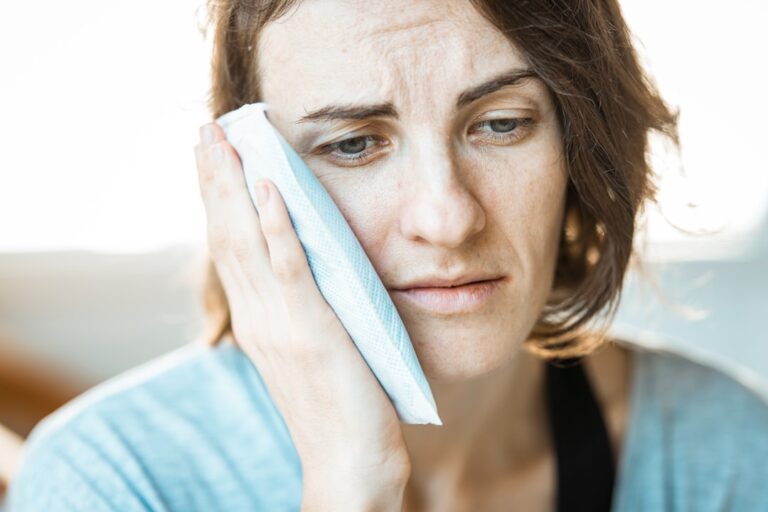 Girl holding her cheek in pain from a toothache, representing an emergency dental visit