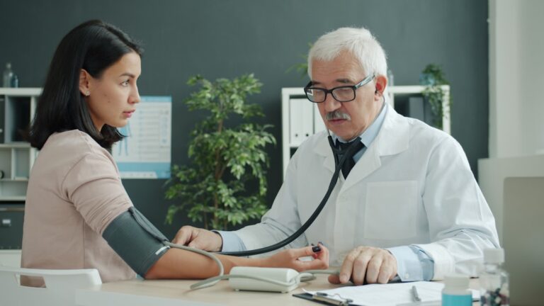 Practitioner checking a young womanu2019s blood pressure during a medical visit