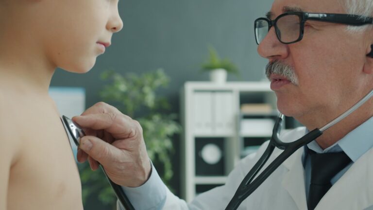 Pediatrician using a stethoscope to examine a young child during a routine checkup