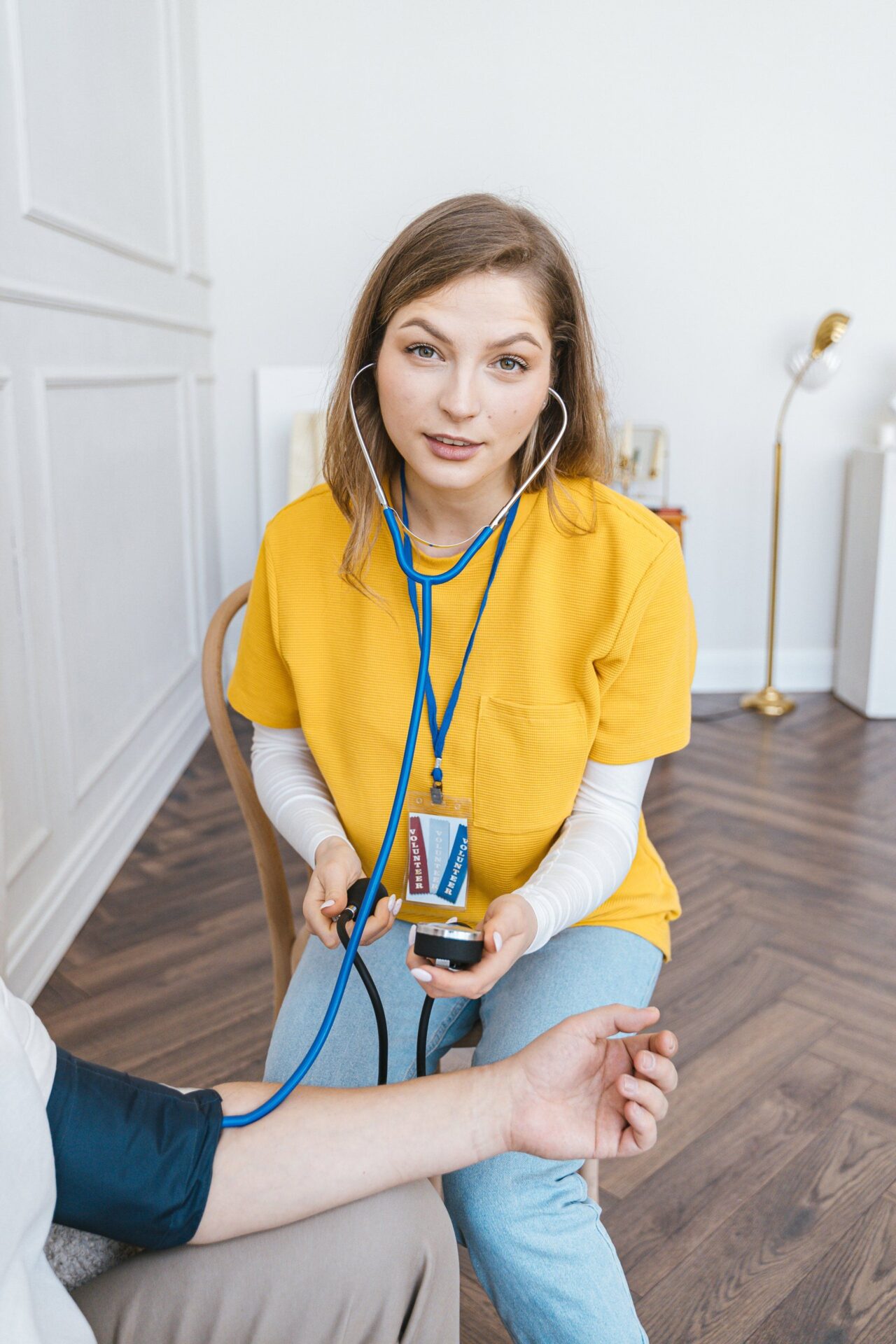 A volunteer wearing a Volunteer badge takes a patient's blood pressure reading